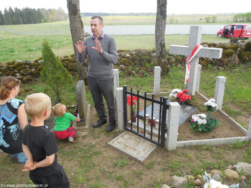 Mężczyzna stoi przy grobie i mówi do dzieci